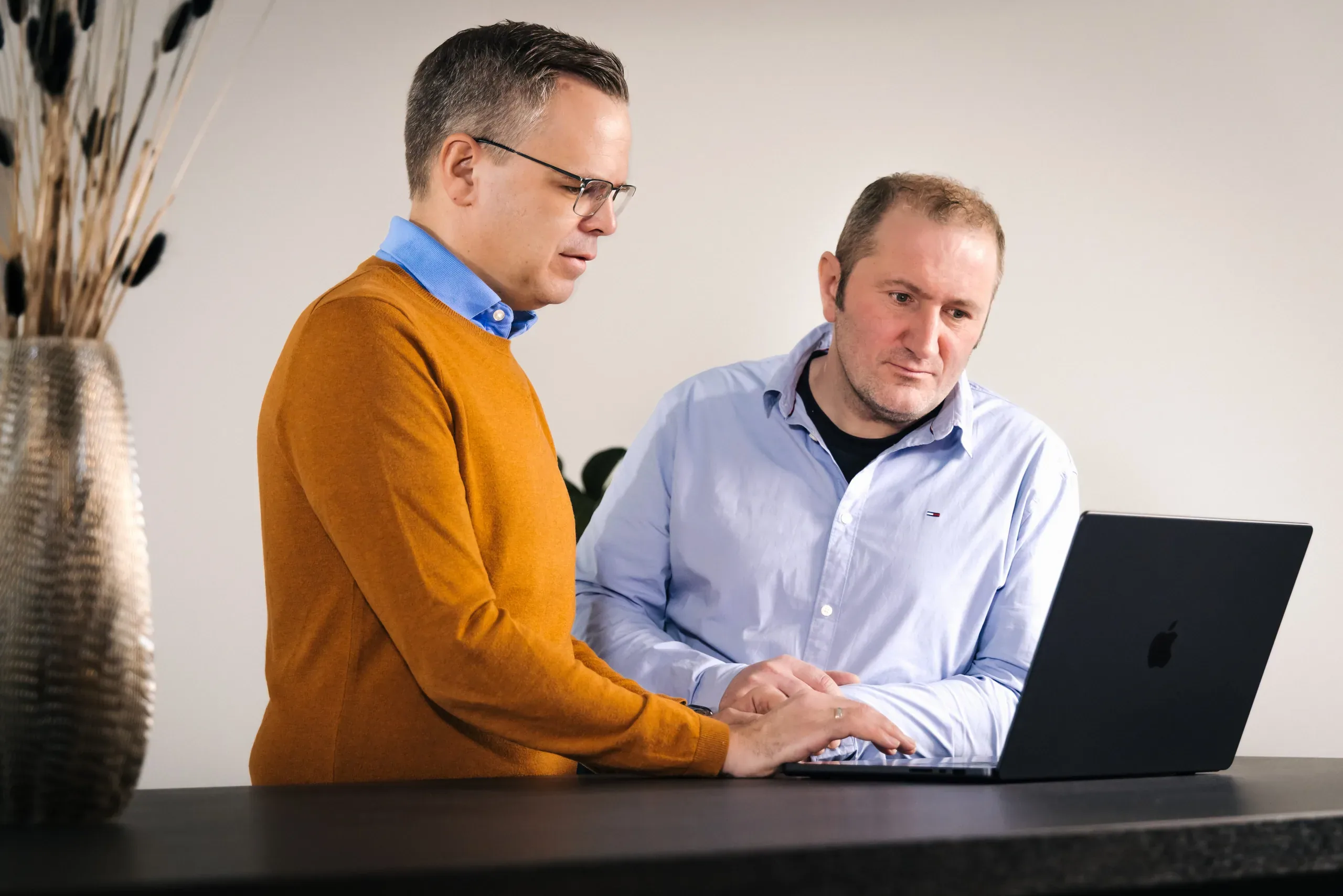 Berater tippt am Laptop während der Kunde daneben steht
